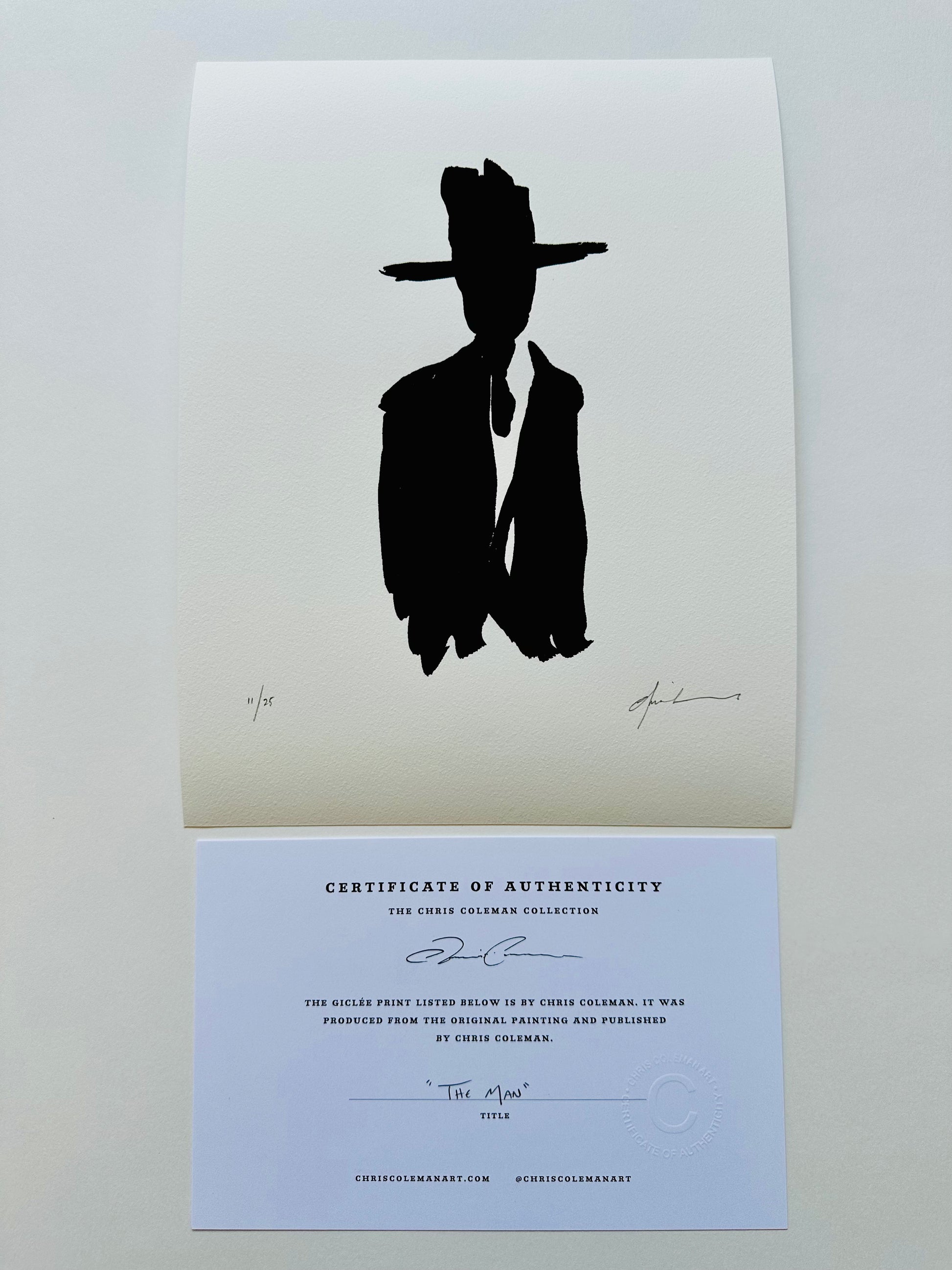 Black silhouette of a man in a cowboy hat, print on white paper, shown with a certificate of authenticity